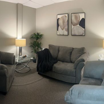 A couch, two chairs, warm lamps, and abstract art furnish the Talk Therapy Room at NCS.