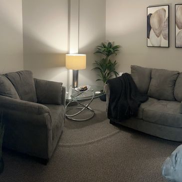 A couch, two chairs, warm lamps, and abstract art furnish the Talk Therapy Room at NCS.