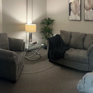 A couch, two chairs, warm lamps, and abstract art furnish the Talk Therapy Room at NCS.