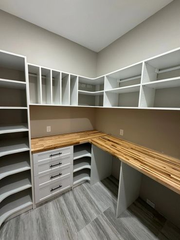 Modern walk-in closet with wooden countertops and ample shelving.