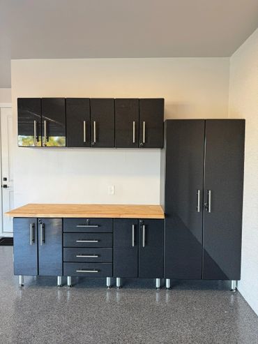 Modern black storage cabinets with a wooden countertop in a clean room.