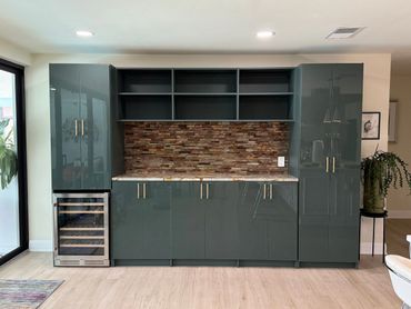 Modern kitchen cabinetry with a built-in wine cooler and textured backsplash.