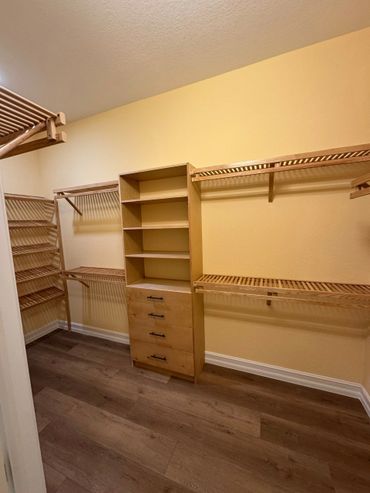 Empty walk-in closet with wooden shelves and drawers.
