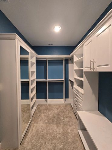 A spacious walk-in closet with white shelves and blue walls.