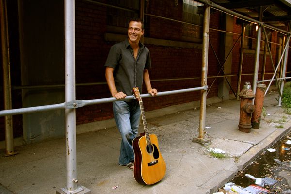 Derek Samuel Reese with his guitar under the Brooklyn Queens Expressway 