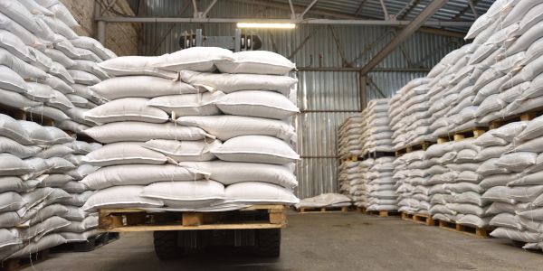Stacks of white sacks on pallets in a warehouse.