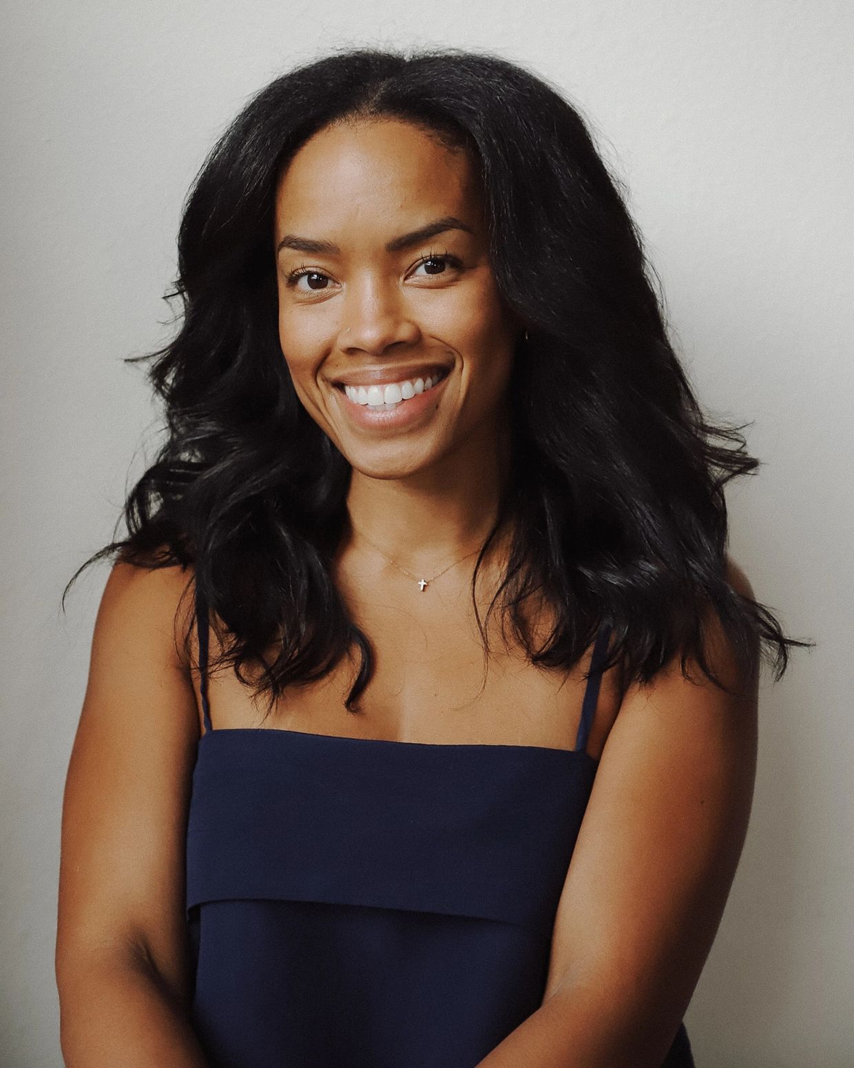Smiling woman with flowing black hair in a navy blue dress.