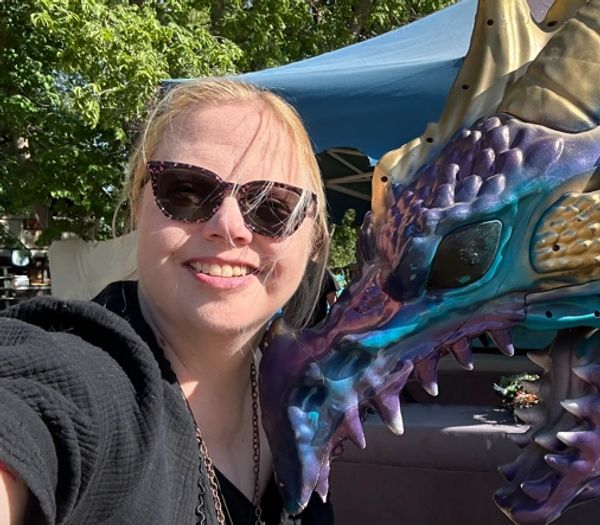 A picture of Tarphy from the shoulders up next to a human-size dragon statue