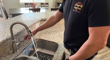 Person turning on kitchen faucet with flowing water.