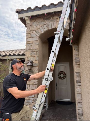 Man setting up a ladder at a house entrance.