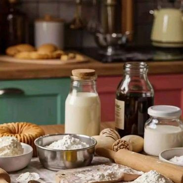 Baking ingredients and tools spread on a wooden kitchen table.