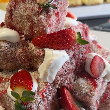 Strawberry-coated dessert cubes topped with cream and fresh strawberries.