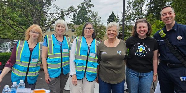 Group of volunteers and a firefighter at an outdoor event.