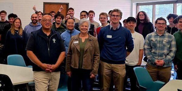 Group photo of diverse people smiling indoors.