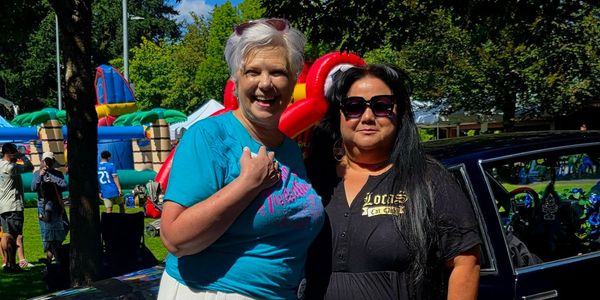 Two women smiling outdoors at an event.