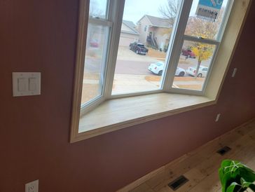 Bay window with wooden sill in a room with purple walls.
