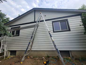 Ladder set up against a house with siding work in progress.