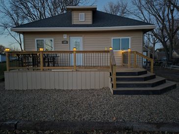 Cozy house with a wooden deck and outdoor seating at dusk.