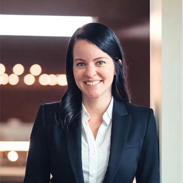 Femme souriante en tailleur noir dans un cadre professionnel.