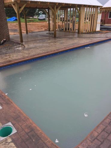 decorative and stained concrete pool with outdoor kitchen