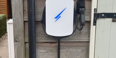 Electric vehicle charging station mounted on wooden wall.