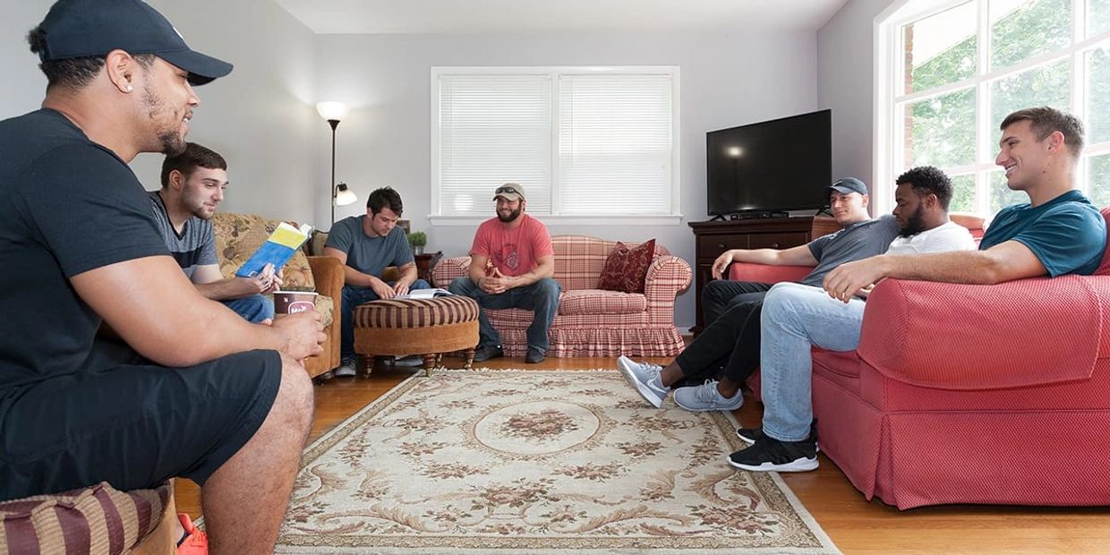 A group of young men sitting and chatting in a cozy living room.