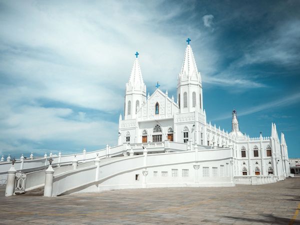 White Gothic church with blue crosses under a cloudy sky.