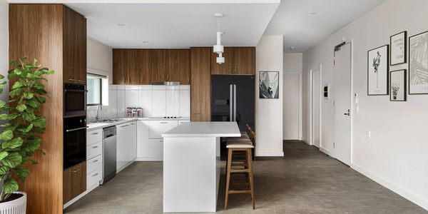 Modern kitchen with wood cabinets, white island, and bar stools.
