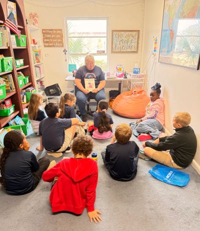 Teacher reading a book to a group of attentive elementary students in a cozy classroom.
