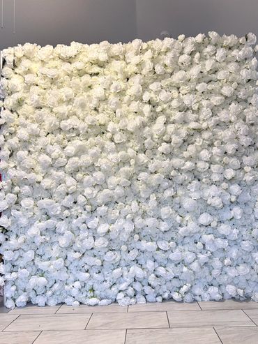Wall covered entirely in white roses with a tiled floor in front.