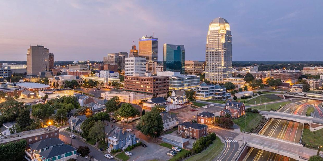City skyline at dusk with illuminated buildings and roads.