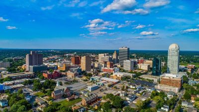 A sunny aerial view of a mid-sized city with prominent buildings and blue sky.
