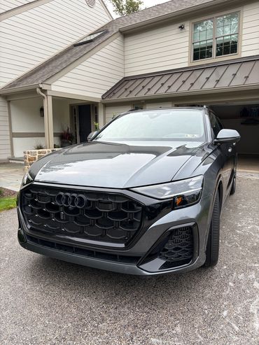 Sleek black Audi SUV parked in front of a modern house.
