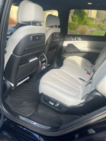Luxurious rear seats with white leather upholstery in a BMW M model car.