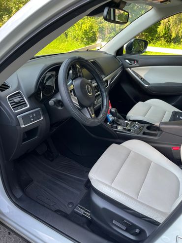 Interior of a Mazda CX-5 showing driver and passenger seats and dashboard.