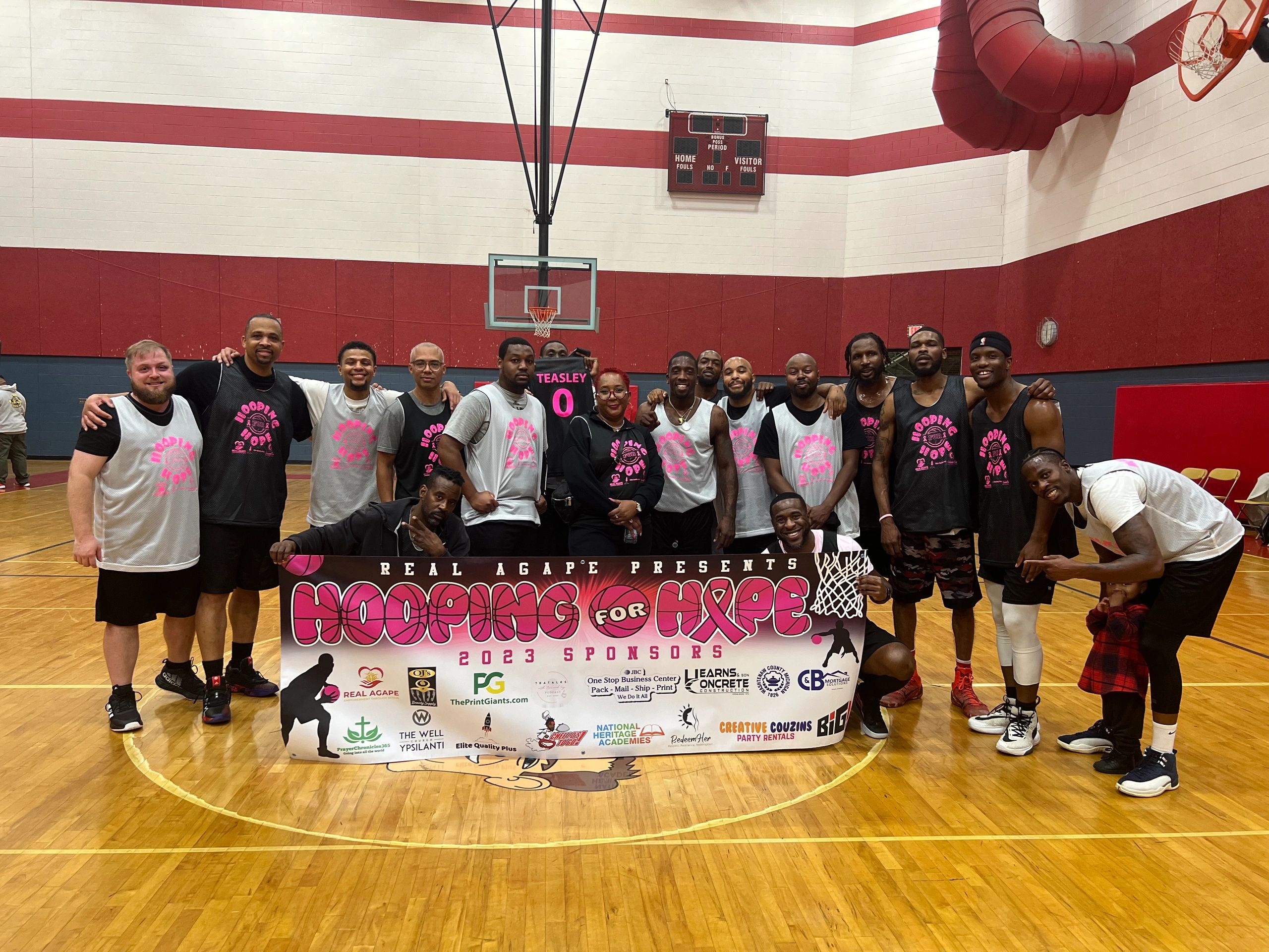 Group photo of basketball players holding a Hooping for Hope banner.