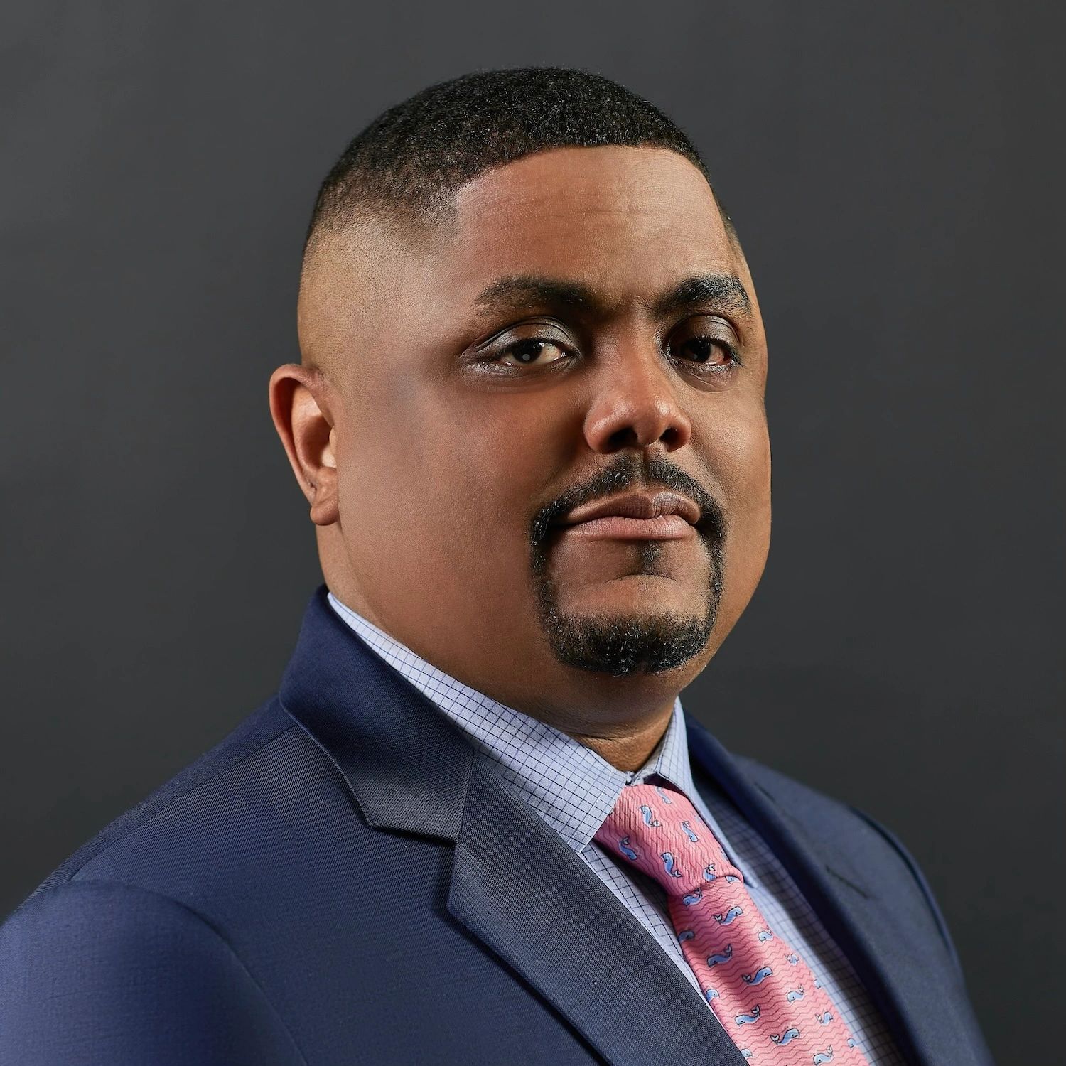 Confident man in a suit and pink tie posing for the camera.