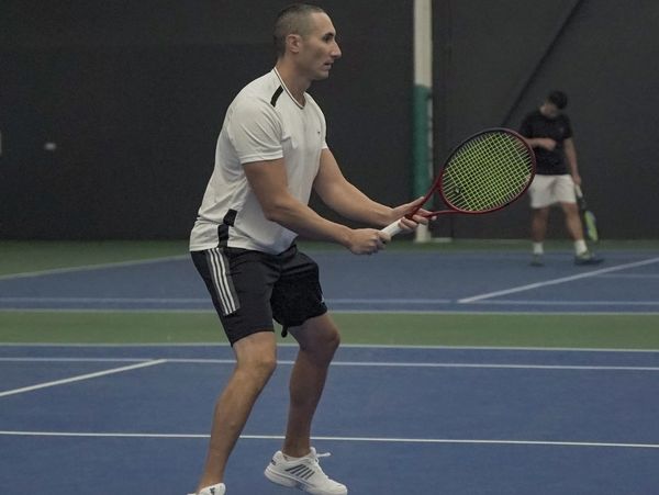 Tennis Coach Jared Bellusci in a ready position at the net