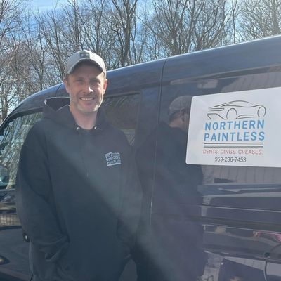Man smiling beside a van with Northern Paintless logo and contact info.