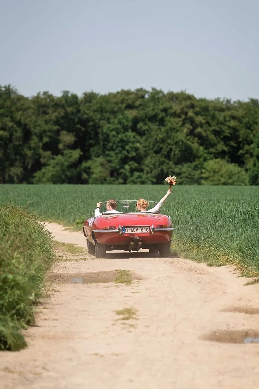 Couple en voiture décapotable sur chemin de campagne.