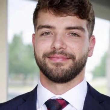 Young man in a suit smiling at the camera.