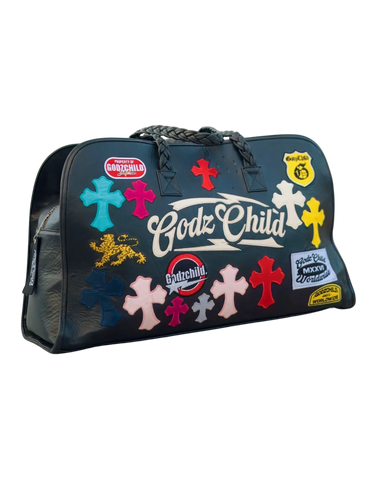 Black Godz Child duffle bag with colorful cross patches and braided handles.