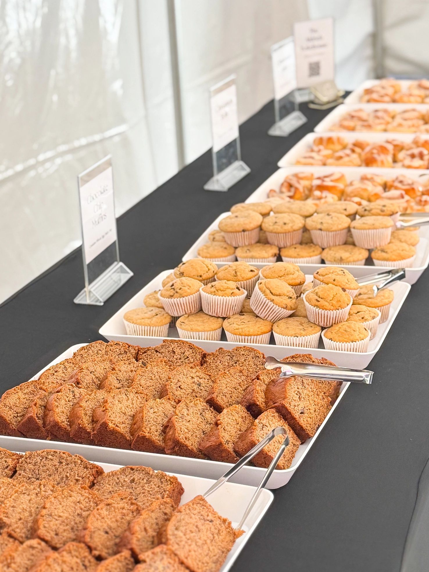 A table with trays of muffins and pastries