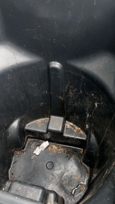 Empty trash bin with some debris inside. Dirty and gross.