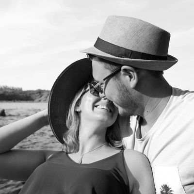 A couple sharing a tender moment outdoors, smiling and closely leaning in.