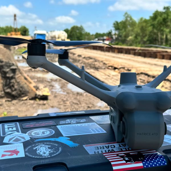 A Matrice 4TD drone resting on a sticker-covered surface at a construction site.