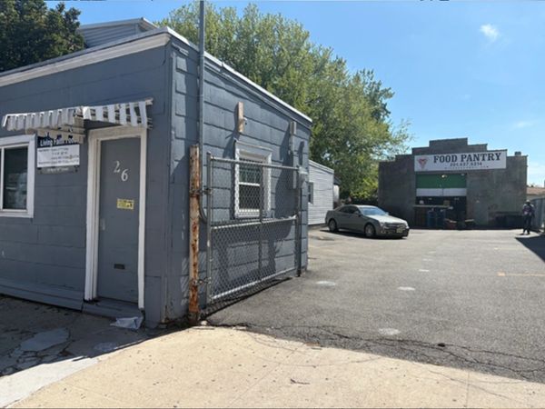 Buildings for a food pantry and living faith outreach center with a parked car outside.