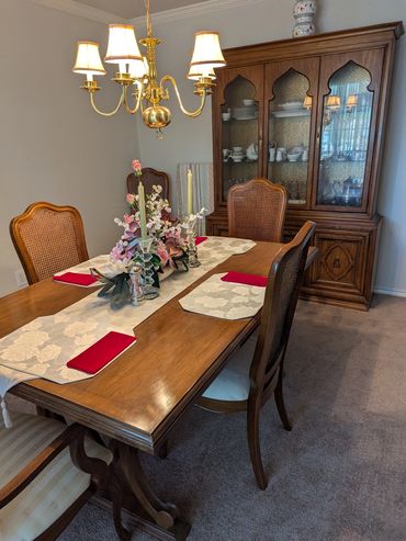 Elegant dining room with wooden furniture and floral centerpiece under warm chandelier light.