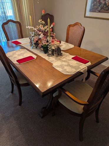 Elegant wooden dining table set with floral centerpiece and red napkins.