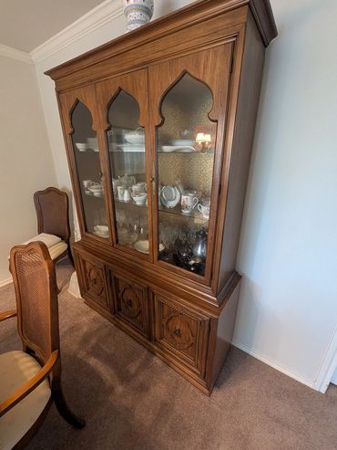 Wooden china cabinet filled with fine dishes and glassware.